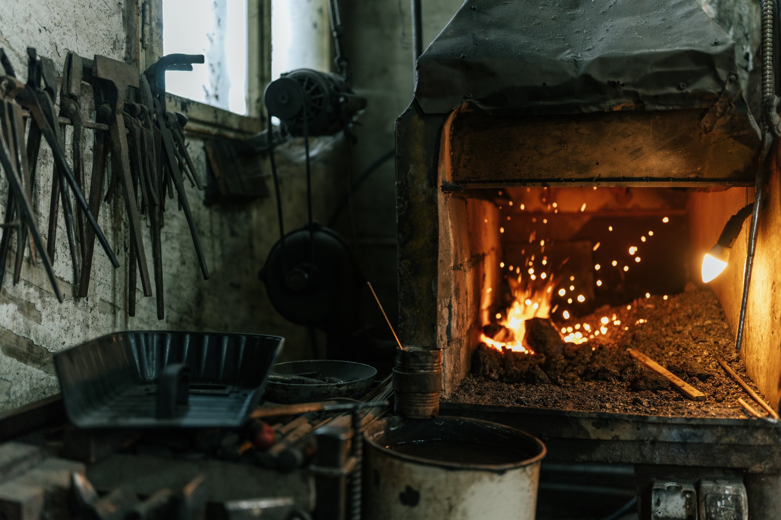 Sparks fly from the glowing coals of the blacksmith’s forge in a stone workshop