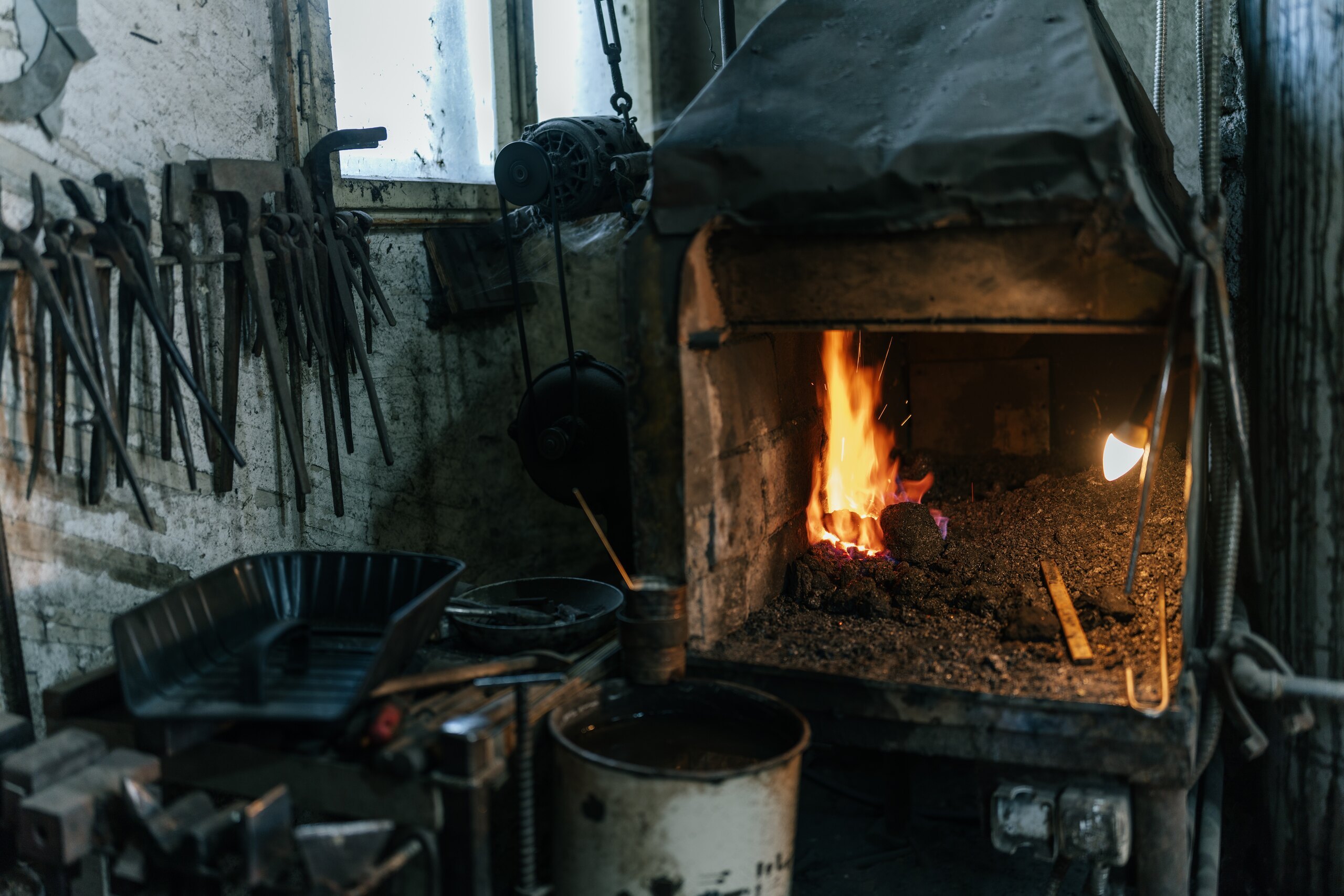 A fire burning in the brick forge of the village blacksmith, tools on the wall