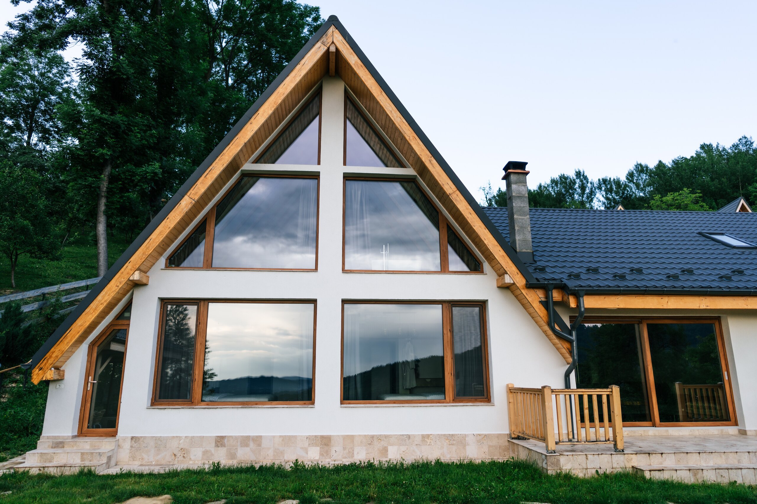 The Mansion: a wide A-frame with a tall glass front, a terrace and a lawn