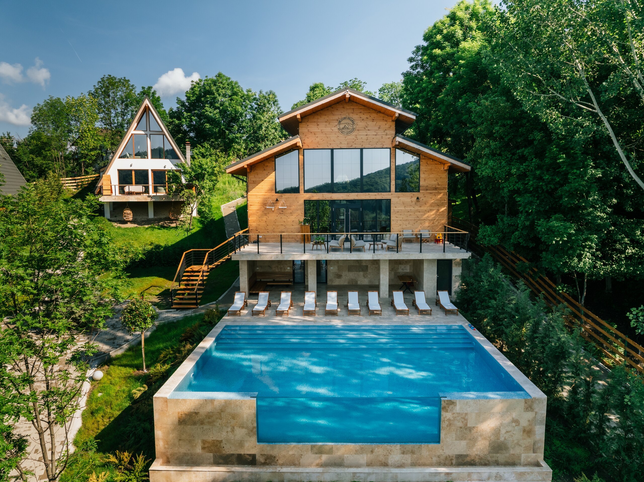 The blue outdoor pool with its stone edge, the Barn and its loungers behind