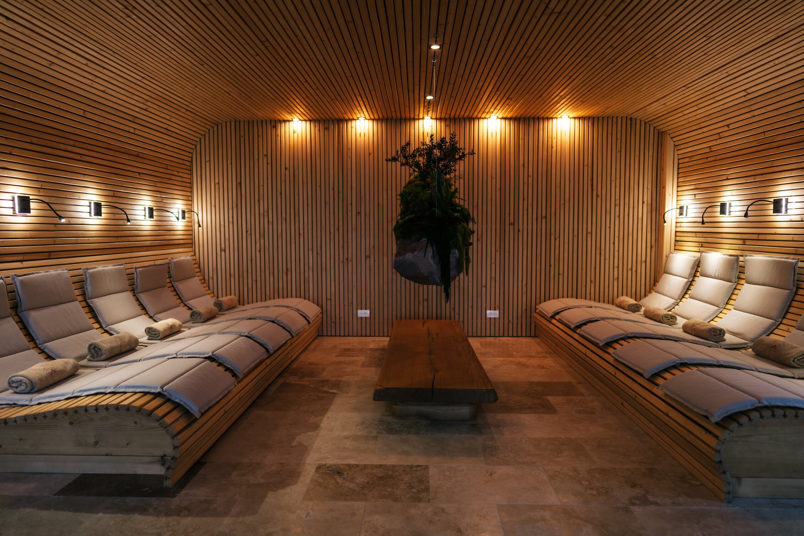 Padded loungers in a wood-panelled spa room lit by small warm lamps