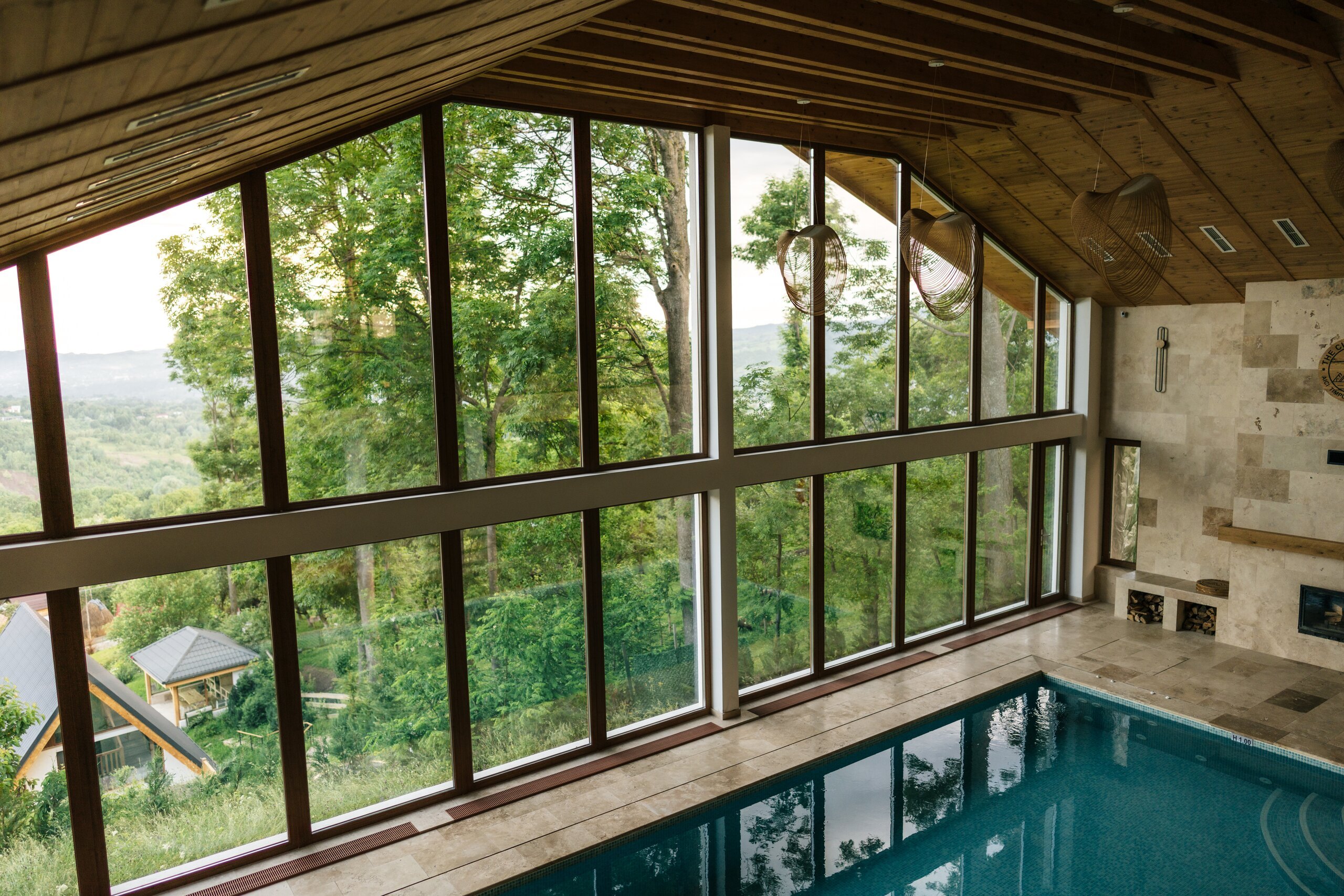 The indoor pool beside tall windows that look out on trees and the valley