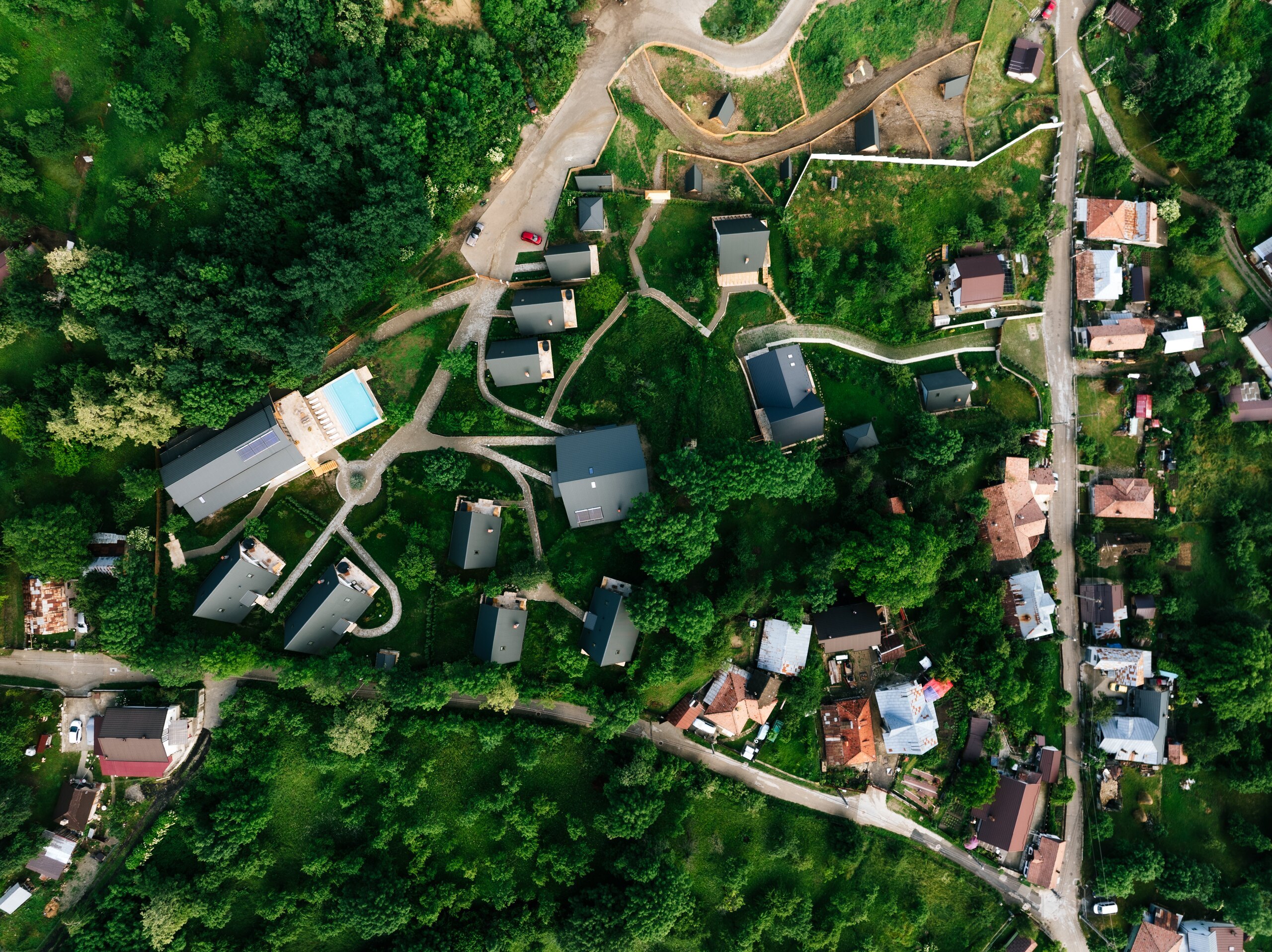 The village seen from straight above: houses, paths and the pool among the trees